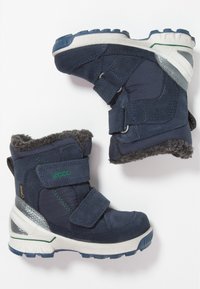 Botas infantiles impermeables de color azul marino, con un suave forro de piel de oveja gris, correas de velcro y una suela de goma texturizada para mayor tracción.
