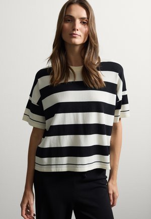 Camiseta oversized a rayas negras y crema con mangas cortas, cuello redondo y un corte relajado, que presenta rayas horizontales y una textura sutil.