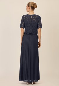 Navy-Abendkleid mit Spitzenoberteil und kurzen Ärmeln sowie einem plissierten Chiffonrock, der ein Rückenschlitz und eine weiche Textur zeigt.