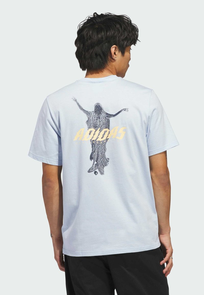 Hellblaues Baumwoll-T-Shirt mit einem schwarzen Grafikdesign auf der Rückseite, mit dem Wort "ADIDAS" in fetten gelben Buchstaben. Kurze Ärmel.