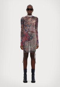 Robe longue en voile à manches longues avec un motif floral dans des tons de violet, rose et vert ; présente un col haut et des accents noués sur les côtés.