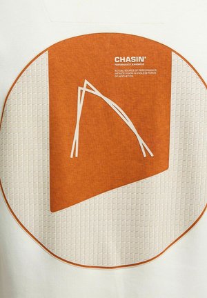 Weißer Stoff mit einer großen kreisförmigen orangen Grafik, die ein geometrisches Design und weiße Linien aufweist. Der Text lautet "CHASIN' PERFORMANCE JEANSWEAR."