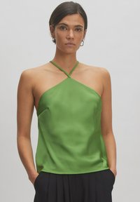 Groene satijnen tanktop met een halterhals en gekruiste banden. Heeft een ontspannen pasvorm en een gladde, glanzende textuur. Kreukvrije stof.
