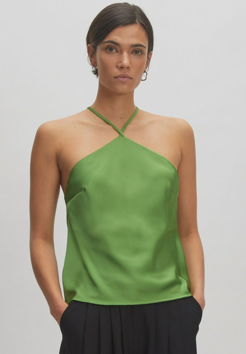 Groene satijnen tanktop met een halterhals en gekruiste banden. Heeft een ontspannen pasvorm en een gladde, glanzende textuur. Kreukvrije stof.