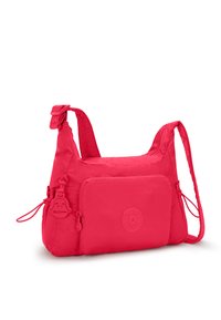 Lys pink crossbody taske lavet af blødt materiale, med en lynlåslomme foran, justerbar rem og en dekorativ vedhæng.