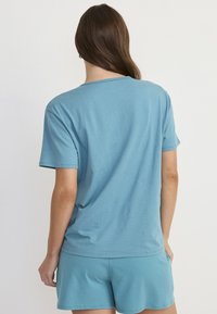 Lichtblauwe katoenen t-shirt met korte mouwen en een ronde halslijn, gecombineerd met bijpassende shorts. Zachte textuur, ontspannen pasvorm.