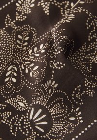 Dark brown fabric featuring intricate cream floral and paisley patterns with delicate dot details, showcasing smooth texture and soft drape.