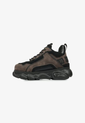 Brown suede sneakers with black shearling accents and black rubber sole. Features a rounded toe and lace-up design with branding on the heel.