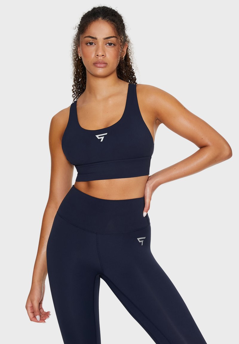 Reggiseno sportivo blu navy e leggings a vita alta; realizzati in tessuto morbido e elasticizzato con un sottile dettaglio del logo sul davanti e sul lato.