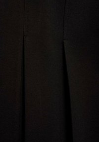 Tessuto nero con due pieghe frontali, texture liscia, design leggero e dettagli di cucitura pulita. Adatto per un abbigliamento formale o casual.
