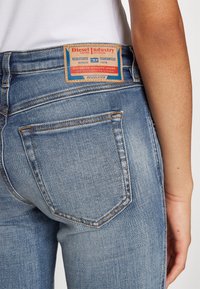 Niebieskie dżinsy z wysokim stanem, z skórzaną metką, przeszytymi tylnymi kieszeniami oraz delikatnym blaknięciem dla uzyskania efektu noszonego.