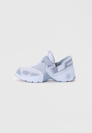 Baskets blanches et gris clair avec tissu en mesh et matelassé, bride Velcro, et semelle épaisse affichant le logo Jordan au talon.