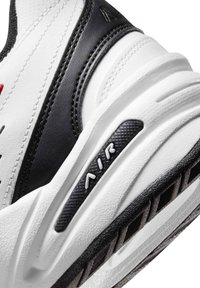 Scarpa sportiva bianca e nera con tomaia in pelle testurizzata e ammortizzazione ad aria visibile con il logo "AIR" ben in vista sulla suola.
