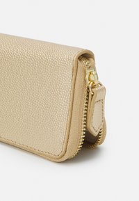 Portafoglio beige textured realizzato in materiale sintetico, con zip e accessori in tonalità oro, dotato di un ulteriore dettaglio con zip sul lato.