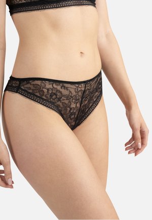 Panties en dentelle noire avec motifs floraux, bords festonnés et texture douce. La taille présente un petit nœud en accent.
