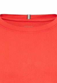 Rød T-shirt med rund hals, der har en glat tekstur. En bemærkelsesværdig detalje er en lodret stribet accent ved baghalsen.