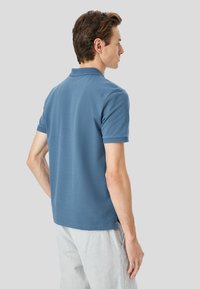 Polo a maniche corte da uomo in cotone blu uniforme, con colletto e polsini strutturati, dal fit rilassato e orlo dritto.