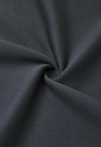 Tessuto nero con una superficie liscia e leggermente texturizzata, esposto in un motivo a spirale, che indica morbidezza e flessibilità.