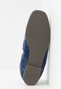 Semelle d'une chaussure en daim bleu tournée vers l'avant avec un motif "KENNEL & SCHMENGER" sur la semelle et le talon en caoutchouc marron.