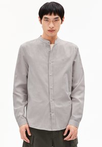 Grijze langslavende shirt met een Mandarin-kraag, voorzijde met knoopsluiting en subtiele textuur. Bevat een klein logo op de borst.