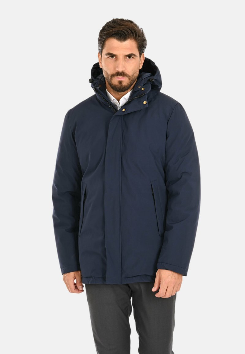 Giacca isolata blu navy con cappuccio, caratterizzata da una cerniera frontale, bottoni a pressione e tasche laterali, realizzata in un tessuto liscio e resistente alle intemperie.