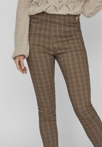 Brown plaid high-waisted pants with a slim fit, featuring a smooth texture and subtle contrasting lines in shades of beige and brown.