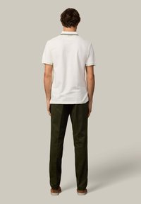 Biela polokošeľa s golierom a dvojfarebným lemom, v kombinácii s tmavozelenými nohavicami. Jednoduchý dizajn, bavlnený materiál a pohodlný strih.