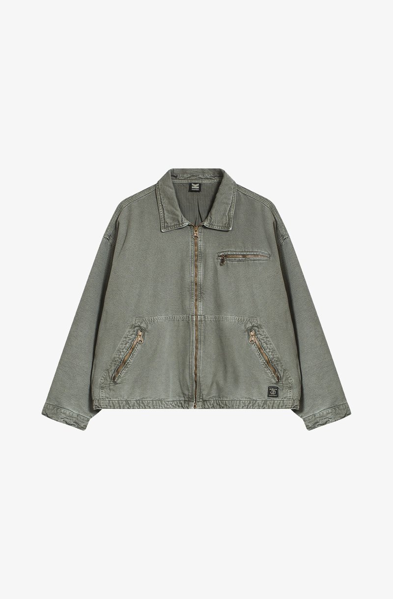 Olajzöld dzseki, gallérral, elülső cipzárral és két oldalsó zsebbel. Tartalmaz egy cipzáros mellzsebet és kontrasztos varrási részleteket.