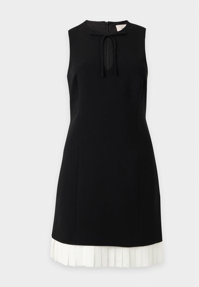 Robe noire sans manches avec décolleté goutte d'eau noué avec un nœud et détail d'ourlet plissé blanc.