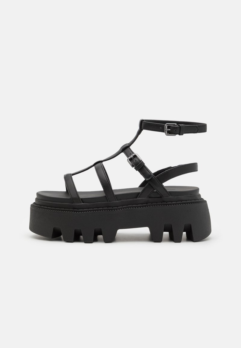 Black platform sandals with multiple thin straps, adjustable ankle buckle, thick textured sole, and a contoured footbed.