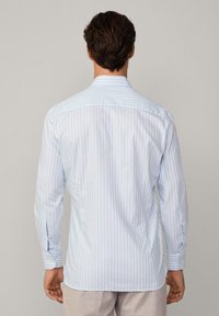 Camicia a righe blu chiaro e bianca, con bottoni, maniche lunghe e polsini; presenta un colletto classico e una texture di tessuto morbida e liscia.