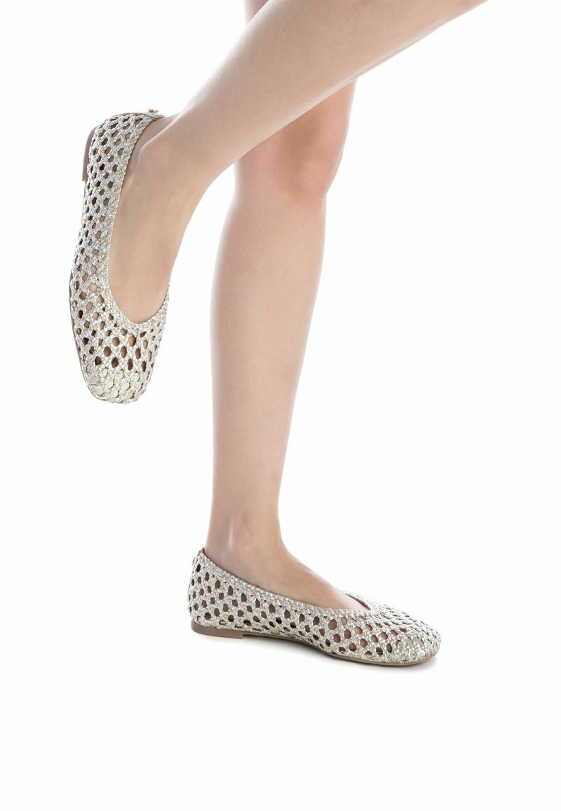 Ballet flats di colore chiaro, intrecciate, con un design aperto e arioso e una suola piatta. La superficie testurizzata presenta un motivo a diamante e una leggera lucentezza.