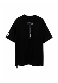 Camiseta negra de gran tamaño fabricada en algodón; presenta mangas cortas, un cuello redondo y una etiqueta en la parte trasera con texto gráfico y detalles del logo.