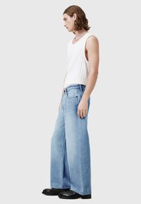 Svetlo modre kavbojke s širokimi nogavicami in visokim pasom, narejene iz jeansa; kombinirane z oprijetim belim topom brez rokavov. Obleko dopolnjujejo črni čevlji.