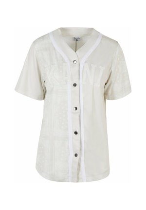 Lichtbeige shirt met korte mouwen, met een knoopsluiting aan de voorkant, witte accenten en gestructureerde patronen; voorzien van "KANI" in verhoogde witte letters.
