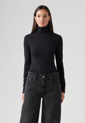 Maglia nera a maniche lunghe con collo alto realizzata in tessuto a coste, design aderente, abbinata a jeans grigi scuri a gamba larga con vita alta.
