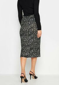 Mustan hameen muotoilu on istuva ja midi-pituinen, ja siinä on valkoisia ja harmaita pilkkuja, jotka täydentävät sileää tekstuuria.