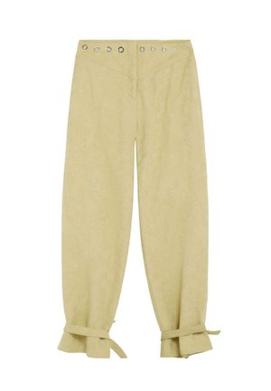 Pantaloni beige chiaro con vita alta, occhielli metallici intorno alla vita e polsini arricciati legati alle caviglie.