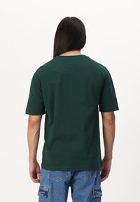 Kortærmet grøn bomulds T-shirt, rund hals, afslappet pasform, glat tekstur, bagudsigt med enkelt design og ingen yderligere detaljer.