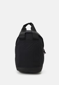 Černý batoh vyrobený z odolného nylonu s kulatým tvarem. Má široké popruhy, strukturované dno a nášivku s logem. Minimalistický design.