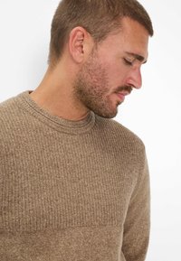 Czekoladowy sweter z dzianiny o ribbowanej teksturze i okrągłym dekolcie. Tkanina wydaje się miękka i ciepła, posiada gładki krój bez wzorów.