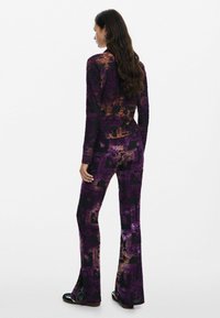 Completo color porpora con motivo, composto da una blusa a maniche lunghe aderente e pantaloni svasati, realizzato in un morbido tessuto con finitura testurizzata.