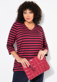 Rood en marineblauw gestreepte longsleeve shirt met een V-hals, gecombineerd met een gewatteerde bordeauxrode clutch met een polsbandje.