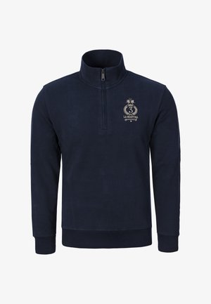 Tmavě modrá mikina s čtvrtým zipem z měkké látky. Má logo na hrudi, žebrované manžety a hladkou texturu.