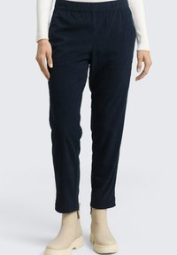 Granatowe prążkowane spodnie z elastycznym paskiem, o zwę�żanych nogawkach, zestawione z kremowymi botkami za kostkę. Teksturowana tkanina z pionowymi paskami.