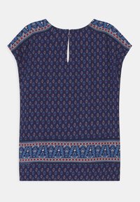 Blusa blu navy con maniche a campana, caratterizzata da un bordo decorativo con motivi rossi e blu. Il dettaglio a chiave sulla schiena aggiunge un accento sottile.