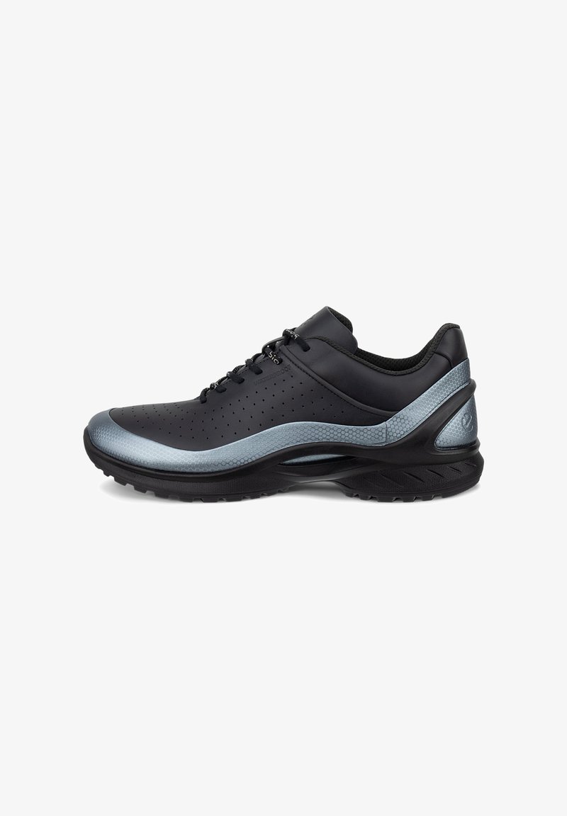 Chaussure de sport noire avec une tige synthétique texturée, des accents gris, des perforations pour la respirabilité et une semelle coussinée.