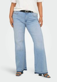 Lichtblauwe wijde jeans met een rafelige zoom, vijf zakken en een zwarte riem met een zilverkleurige dubbele cirkelgesp. Glad denimtextuur.