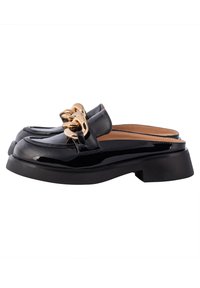 Mocassins noirs en cuir verni à enfiler avec un gros détail de chaîne dorée et un petit talon bloc, arrière ouvert pour faciliter l'enfilage.