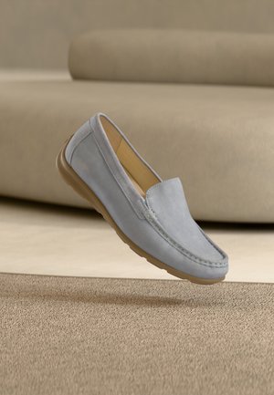 Lichtblauwe suède loafers met een gladde textuur, een afgeronde neus en een rubberen buitenzool, weergegeven boven een beige tapijt.